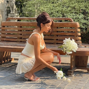 Detail shot of a cream ruffled camisole and mini skirt set worn in a garden setting
