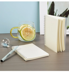 Detail of spiral bound notebook with 0.5mm pen on a minimalist blue desk