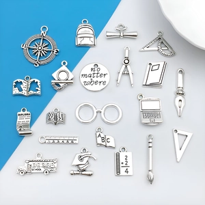 Detailed flat lay of 21 antique silver alloy charms with graduation and school themes