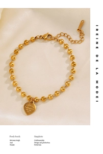 Detailed macro view of gold beaded stainless steel heart bracelet on silk fabric