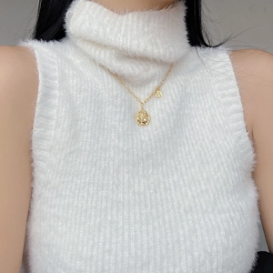 Detail of vintage gold portrait coin necklace on white fuzzy knit turtleneck sweater