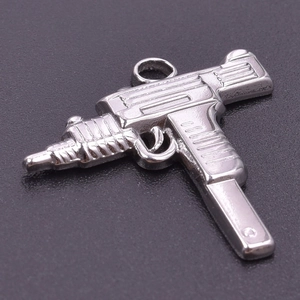Macro shot of silver Uzi gun pendant with polished texture and detailed engraving