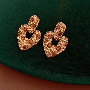 Détail de boucles d'oreilles cœur vintage avec zircons ambre sur support velours