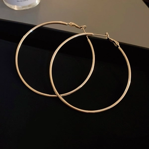 Close-up of elegant gold hoop earrings on a black tray with smooth metallic finish