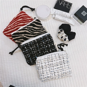Macro detail of tweed and zebra pattern makeup pouches with secure zipper closures