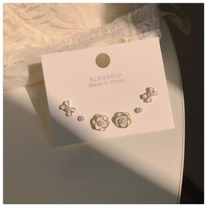 Detail view of pearl earring set featuring white enamel camellia and bowknot designs