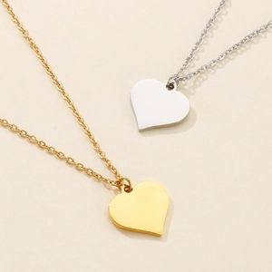 Flat lay of polished gold and silver heart pendants on delicate stainless steel chains