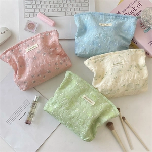 Flat lay of macaron-colored cosmetic bags with textured rose pattern and zipper