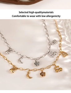 Detail of stainless steel bracelets with moon, cherry, and rose charms on a beige surface