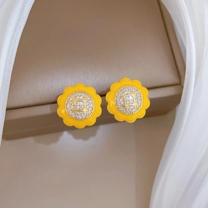 Detail of yellow flower earrings with crystal center on a luxury jewelry box display