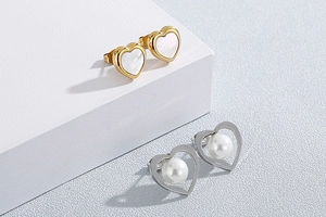 Detailed view of heart-shaped earrings with mother of pearl and pearl on a podium
