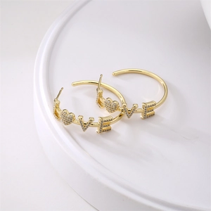 Detailed shot of golden hoop earrings featuring LOVE letters and heart shaped crystals