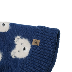 Detail der blauen Strickmütze mit Plüschbären-Aufnäher und braunem Leder-Markenetikett