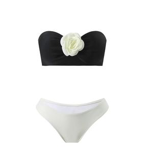 Detail of bikini set featuring a 3D white rose on a black bandeau top and white bottoms