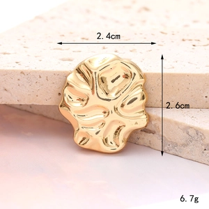 Macro de un adorno de zapato corazón dorado de 2,4cm con textura ondulada sobre piedra