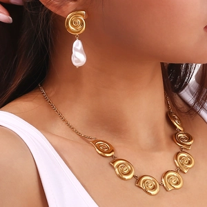 Detail of 18K gold plated spiral snail necklace and baroque pearl drop earrings set on model