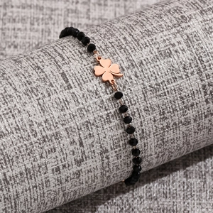 Detail of faceted black beads bracelet with rose gold clover charm on display stand