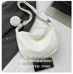 Detailed view of white quilted crescent bag with adjustable strap and small coin pouch