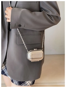 Silver mini metal chain bag with vertical ridges worn by a model in a fashion outfit