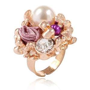 Gros plan d'une bague dorée réglable avec rose en tissu rose, perle blanche et perles violettes