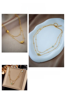 Detail of layered gold chain necklace with blue evil eye pendants and jewelry box packaging