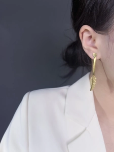 Detail of gold leaf dangle earring with brushed texture on a side-profile model