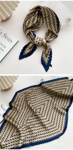 Detail of pleated silk scarf showing navy and champagne diagonal stripes and texture