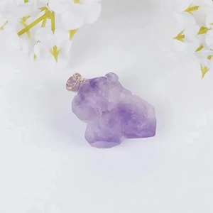 Natural raw amethyst quartz pendant carved in mythical beast shape on white background