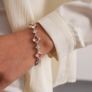 Détail d'un bracelet trèfle de luxe avec pierre rose et zircons au poignet d'une femme