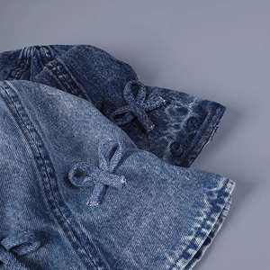 Vue détaillée du chapeau de soleil en denim avec nœuds et détails de coutures texturées