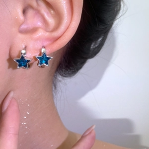 Detailed close-up of zircon flower earrings with silver finish and blue stones