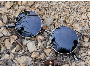 Macro detail of retro round punk sunglasses with metallic frame on outdoor stones