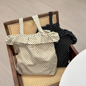 Close-up of polka dot canvas tote bags with ruffle trim on a vintage chair