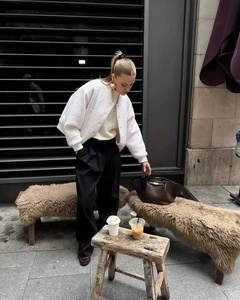 Outdoor street style view of a white fleece bomber jacket with black wide-leg trousers