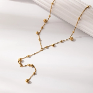 Elegant gold-plated ball fringe Y-necklace displayed on a white textured column base