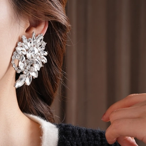 Close-up of a silver flower earring with sparkling crystal petals on a female model