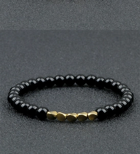 Macro detail of elastic beaded bracelet with black lava beads and golden heart spacers