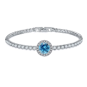 Close-up of silver tennis bracelet with a round blue gemstone and halo pavé setting