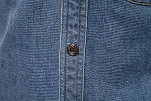 Détail du bouton métallique avec gravure FASHION et double couture sur chemise en jean