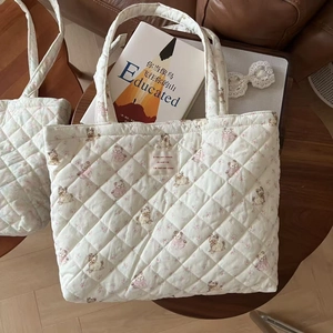 Detail of quilted cotton tote bag with vintage poodle and floral print on a wooden stool