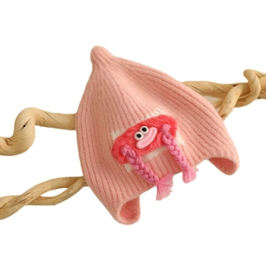Pink knit baby beanie with cute cartoon monster and braided earflaps for winter warmth