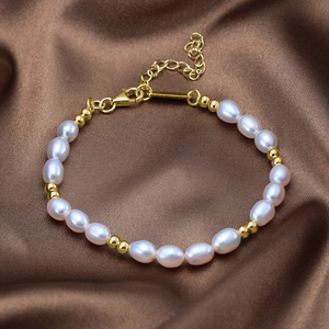 Detail of freshwater pearl bracelet with gold beads on brown silk texture background