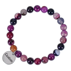 Macro detail of elastic purple agate bead bracelet with custom engraved metal pendant