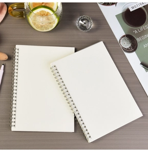 Detail of white spiral notebook with cream paper on a minimalist desk with stationery