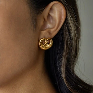 Luxurious gold twisted heart stud earrings in titanium steel worn by a model