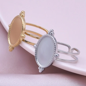 Macro detail of gold and silver oval bezel rings with beaded edges on a pink dish