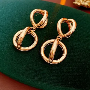 Minimalist twisted double circle gold earrings on dark green velvet jewelry box display