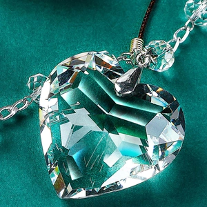 Car mirror pendant featuring a heart-shaped faceted crystal with a metal cross and woven rope