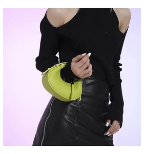 Green crescent moon bag with lychee grain texture and gold hardware held by a model