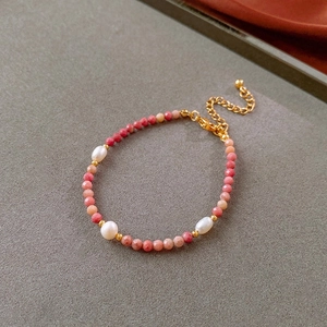 Detail view of pink and orange faceted beads with white freshwater pearls and gold clasp